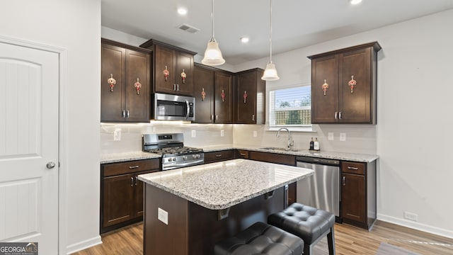 kitchen featuring sink, a center island, hanging light fixtures, stainless steel appliances, and a kitchen breakfast bar