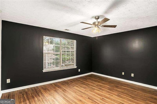 empty room featuring ceiling fan, wood-type flooring, and a textured ceiling