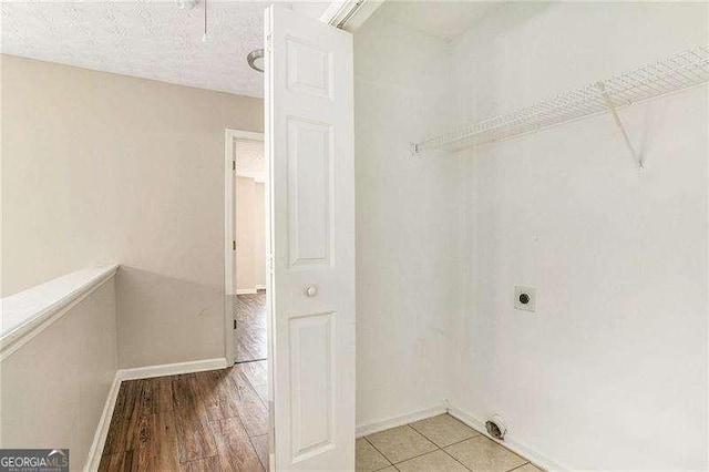 clothes washing area featuring hookup for an electric dryer and light wood-type flooring