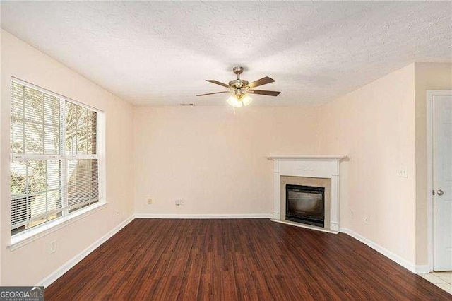 unfurnished living room with a textured ceiling, plenty of natural light, and dark wood-type flooring