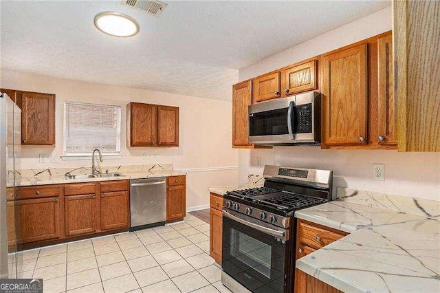 kitchen with a textured ceiling, light tile patterned flooring, sink, and stainless steel appliances