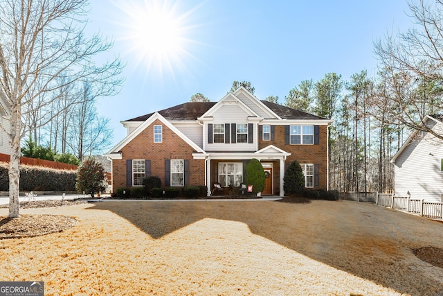 view of front of home featuring driveway, fence, and brick siding