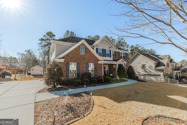 traditional-style home featuring driveway, brick siding, a front lawn, and fence