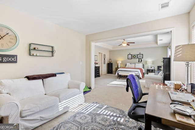 home office featuring ceiling fan, a tray ceiling, and carpet floors