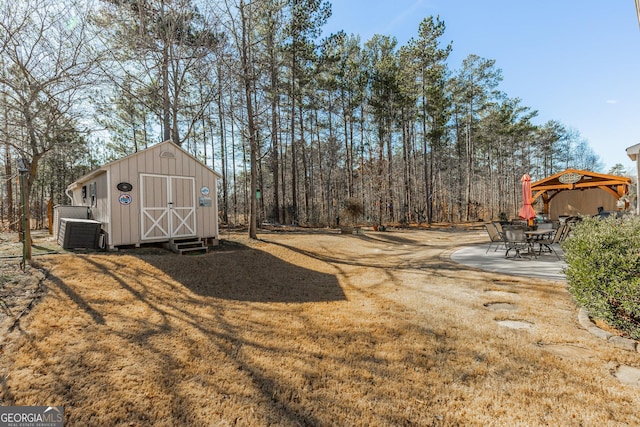 view of yard featuring a storage shed, a gazebo, a patio area, and central AC