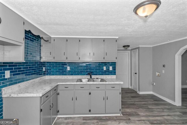 kitchen featuring backsplash, sink, dark hardwood / wood-style floors, gray cabinets, and ornamental molding