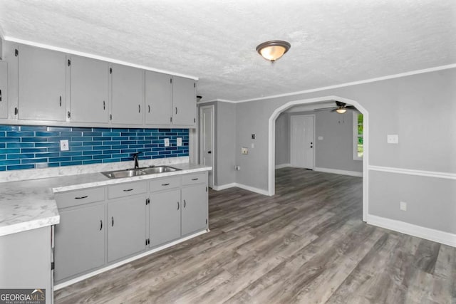 kitchen with gray cabinetry, crown molding, sink, ceiling fan, and dark hardwood / wood-style flooring