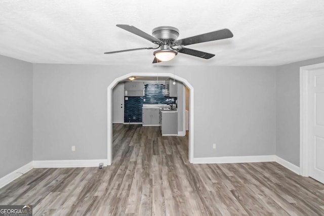 unfurnished living room featuring ceiling fan, sink, a textured ceiling, and hardwood / wood-style flooring