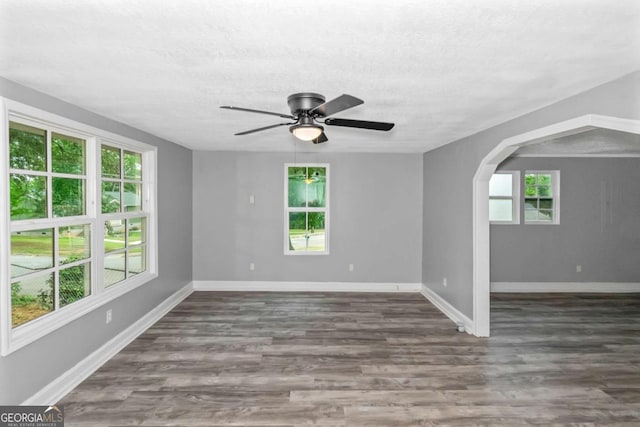 empty room featuring a textured ceiling, ceiling fan, and dark hardwood / wood-style floors