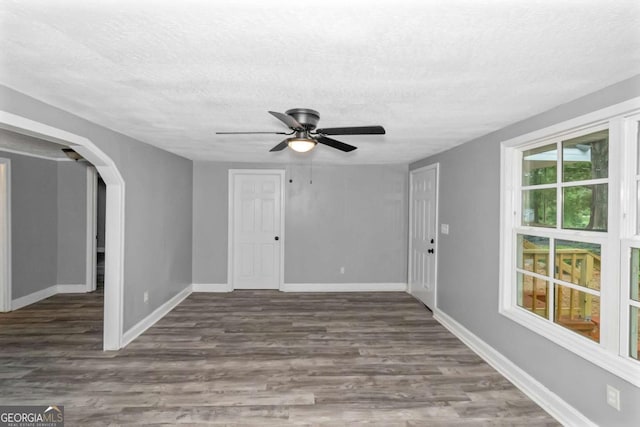 unfurnished room with ceiling fan, dark wood-type flooring, and a textured ceiling