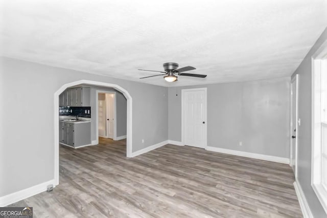 unfurnished living room featuring ceiling fan, light hardwood / wood-style floors, and sink