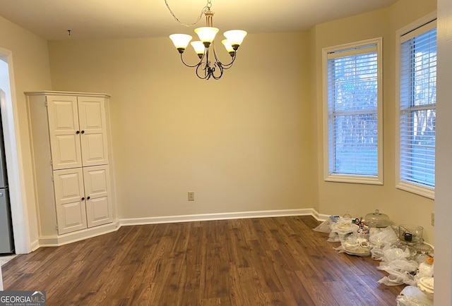 unfurnished room featuring an inviting chandelier and dark wood-type flooring