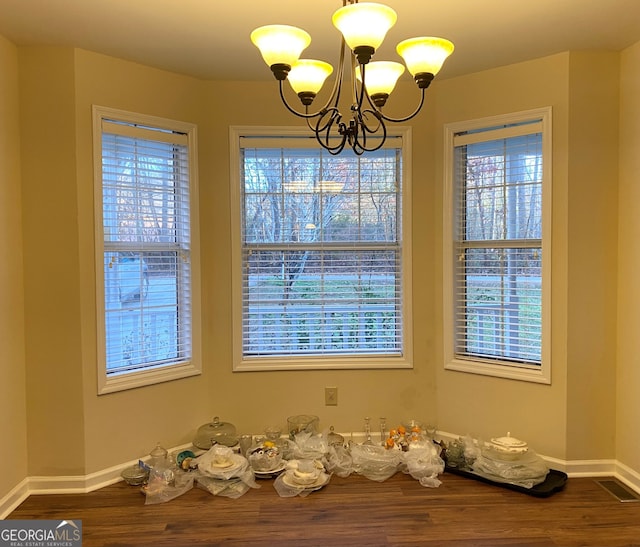 unfurnished dining area with a notable chandelier and wood-type flooring