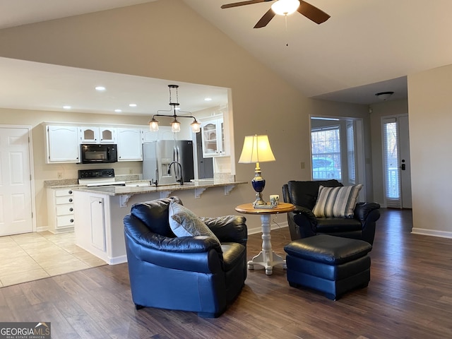 living room featuring ceiling fan, light wood-type flooring, and high vaulted ceiling