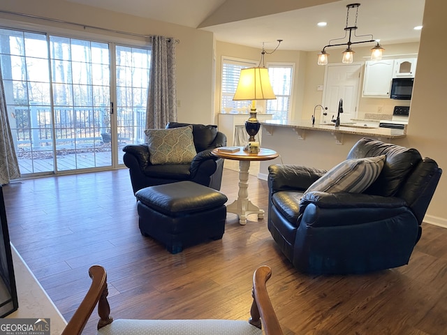 living room with hardwood / wood-style floors, a healthy amount of sunlight, and lofted ceiling