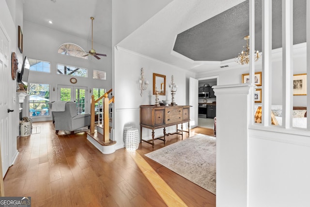 interior space with hardwood / wood-style floors, a tray ceiling, ornamental molding, and a towering ceiling