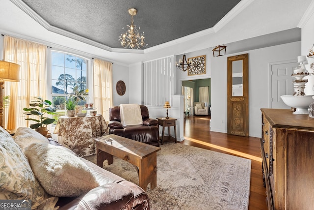 living room featuring crown molding, dark wood-type flooring, a textured ceiling, a raised ceiling, and a chandelier