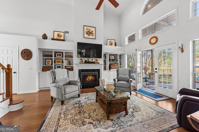 living room with hardwood / wood-style flooring, a high ceiling, ceiling fan, and built in shelves