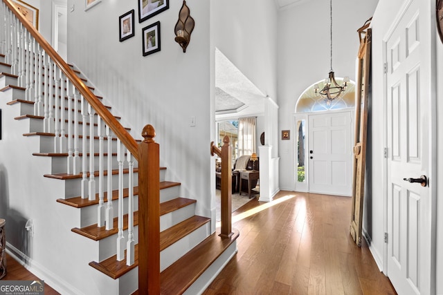 entrance foyer featuring a towering ceiling, wood-type flooring, and a chandelier