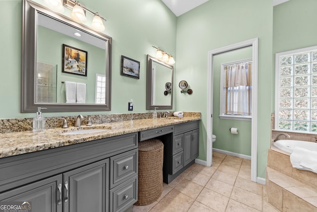 bathroom featuring vanity, a relaxing tiled tub, tile patterned floors, and toilet