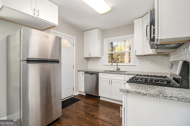 kitchen featuring light stone countertops, sink, dark hardwood / wood-style floors, white cabinets, and appliances with stainless steel finishes