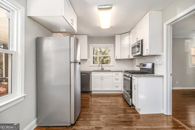 kitchen with sink, dark wood-type flooring, stainless steel appliances, backsplash, and white cabinets