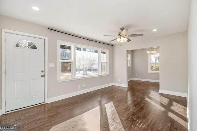 foyer entrance with dark hardwood / wood-style flooring and ceiling fan with notable chandelier