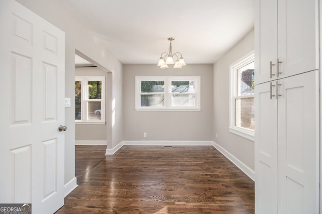 unfurnished dining area featuring dark wood-type flooring and an inviting chandelier