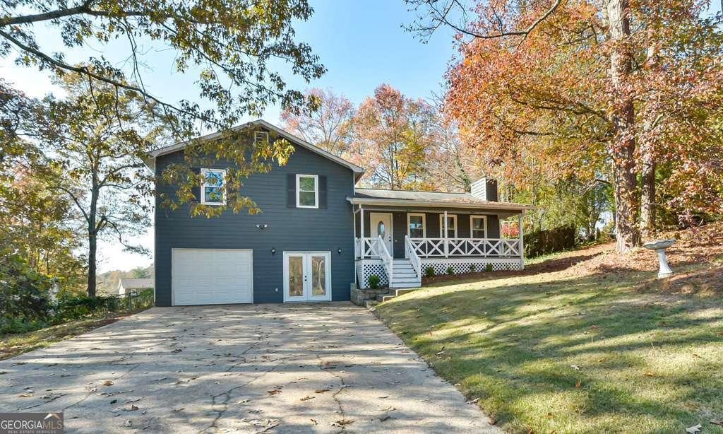 tri-level home featuring covered porch, french doors, a garage, and a front lawn