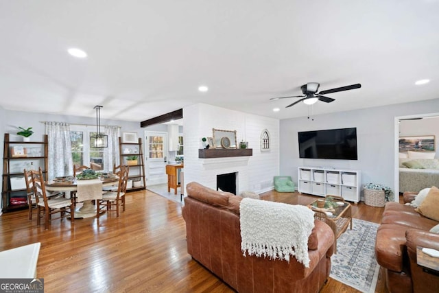 living room featuring hardwood / wood-style flooring, a large fireplace, and ceiling fan