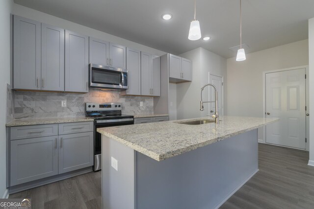 kitchen with appliances with stainless steel finishes, gray cabinetry, sink, pendant lighting, and dark hardwood / wood-style floors