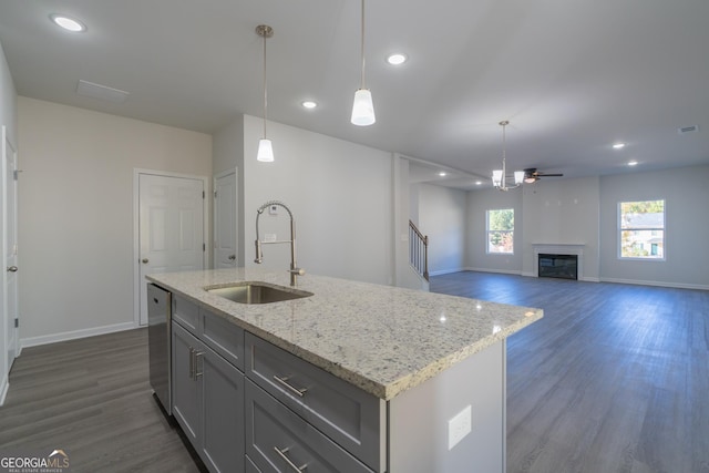 kitchen featuring dark hardwood / wood-style flooring, ceiling fan, sink, decorative light fixtures, and a center island with sink