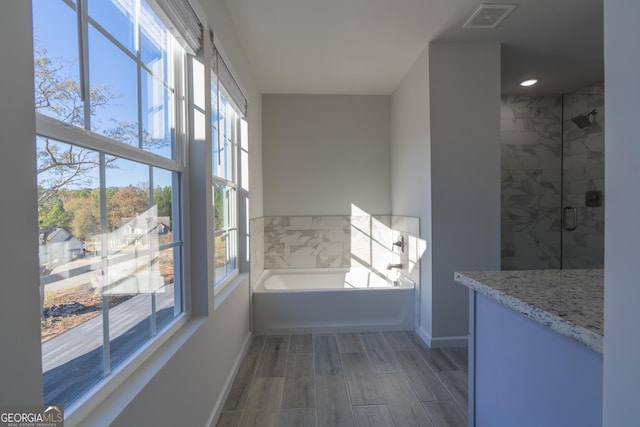 full bathroom featuring a garden tub, wood finish floors, visible vents, baseboards, and a stall shower