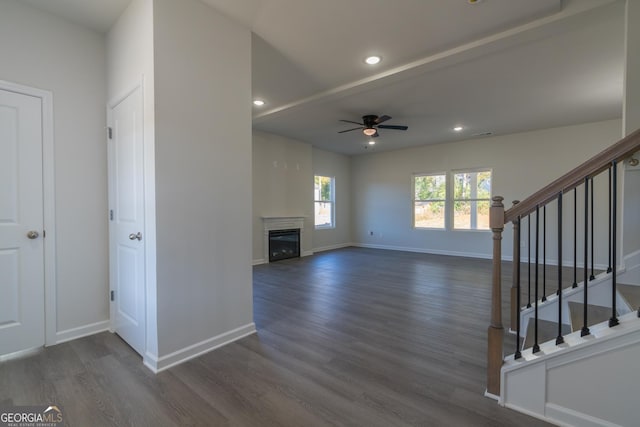 unfurnished living room with recessed lighting, dark wood finished floors, baseboards, stairway, and a glass covered fireplace