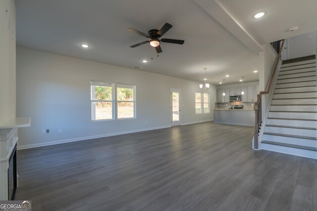 unfurnished living room with ceiling fan, a healthy amount of sunlight, and dark hardwood / wood-style floors