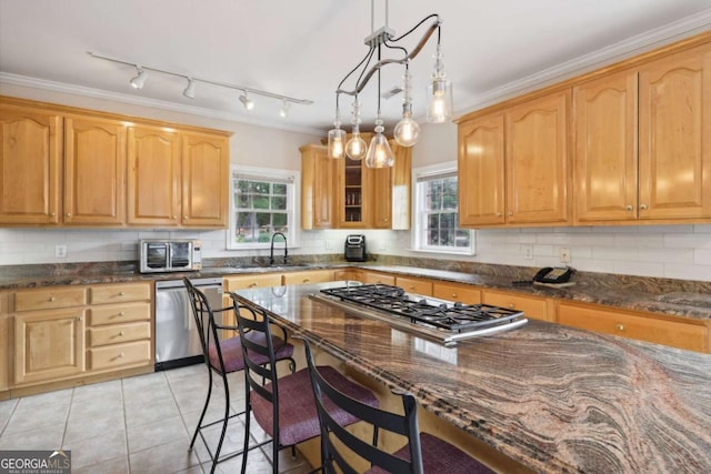 kitchen with appliances with stainless steel finishes, crown molding, light tile patterned floors, pendant lighting, and dark stone countertops