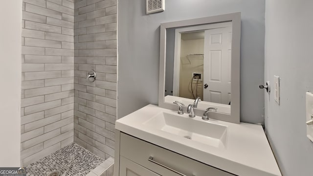 bathroom featuring a tile shower and vanity