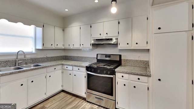 kitchen featuring sink, stainless steel range with gas cooktop, light hardwood / wood-style flooring, decorative backsplash, and white cabinets