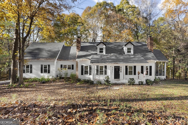 new england style home with covered porch and a front lawn