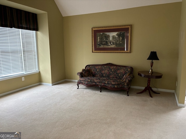 living area with light colored carpet, a healthy amount of sunlight, and lofted ceiling