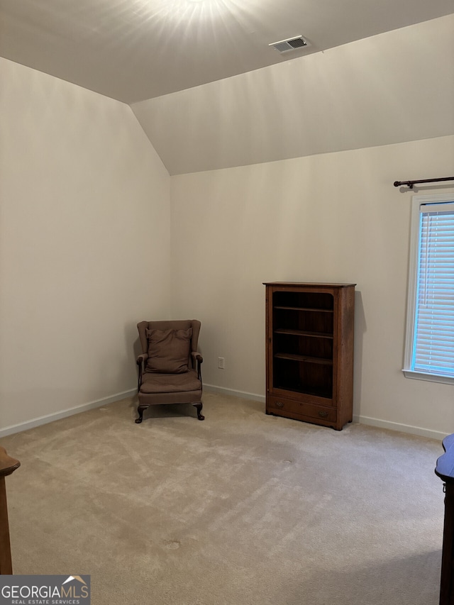 living area featuring light carpet and vaulted ceiling