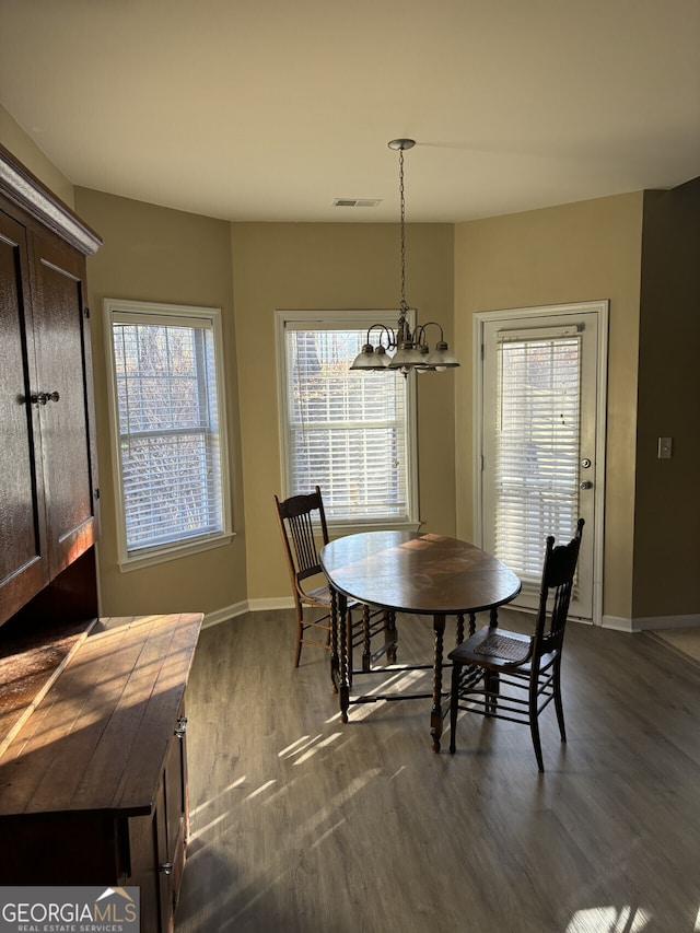 dining area with a wealth of natural light, dark hardwood / wood-style flooring, and a chandelier