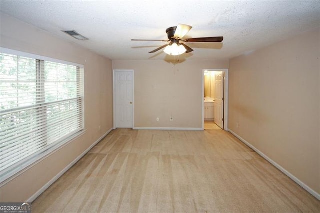 unfurnished room with ceiling fan, light colored carpet, and a textured ceiling