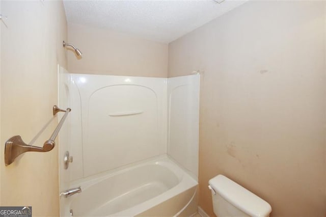 bathroom with toilet, a textured ceiling, and bathing tub / shower combination