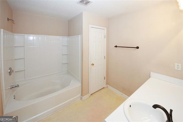 bathroom with a textured ceiling, vanity, and tub / shower combination