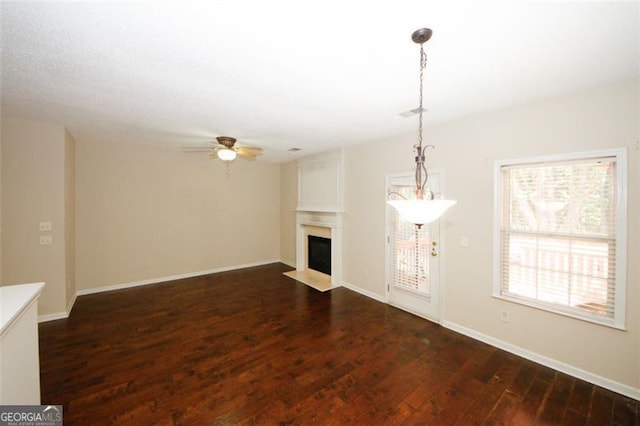 unfurnished living room featuring ceiling fan and dark hardwood / wood-style flooring