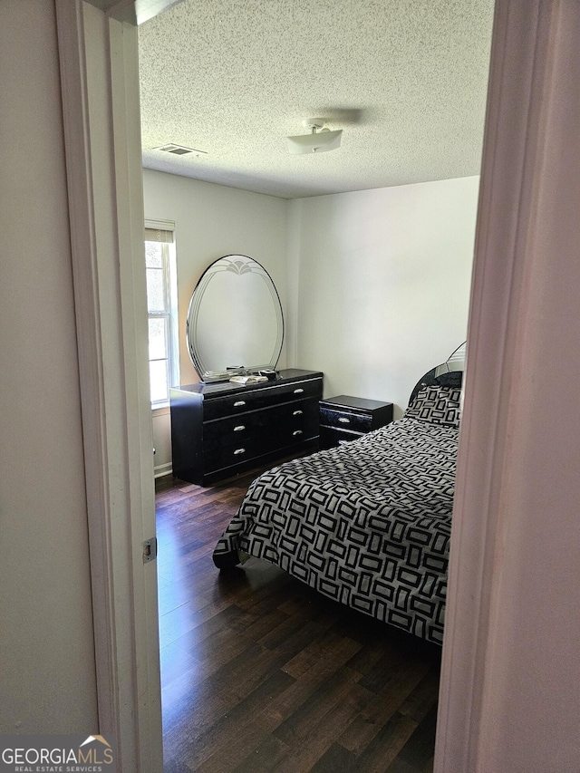 bedroom featuring dark hardwood / wood-style floors and a textured ceiling