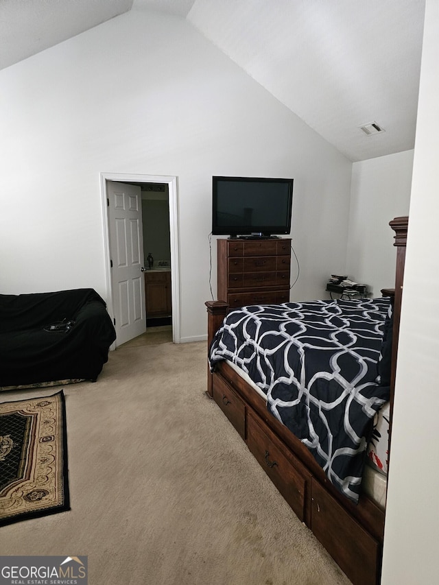 carpeted bedroom with ensuite bathroom and vaulted ceiling