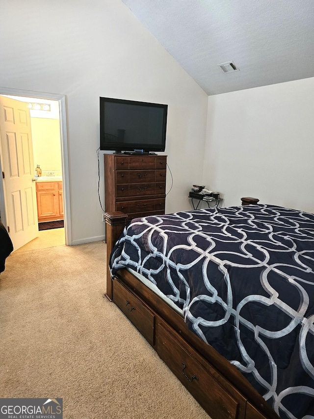 bedroom featuring light colored carpet, a textured ceiling, connected bathroom, and vaulted ceiling