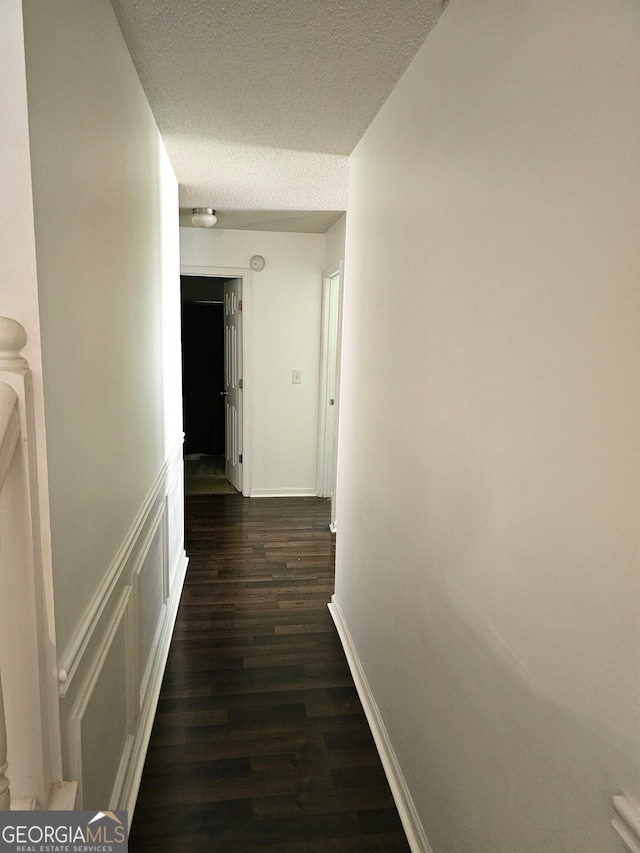 hallway featuring dark wood-type flooring and a textured ceiling